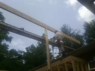 Carpenter setting a ridge beam over a new addition frame — Ice Dam Removal by Roofing Brothers in Huron