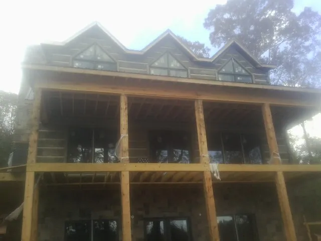 Dormers and porch framing on a large log home under construction — Roof Coating work by our crew in Huron