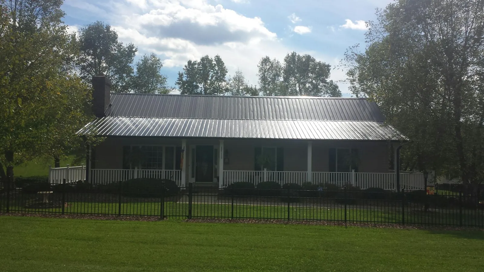 Gray metal roof on a brick ranch with a full width front porch — Gutter Guard Installation work by our crew in Huron