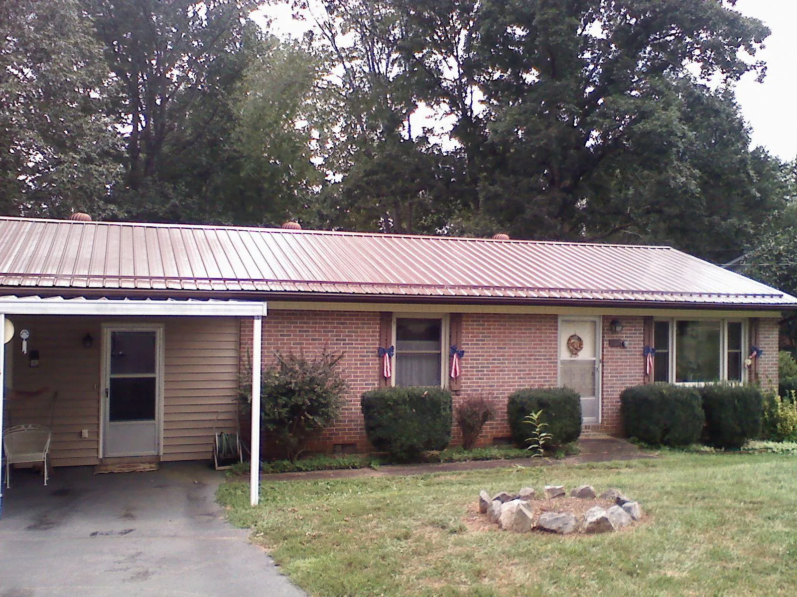 Bronze metal roof and carport on a brick ranch home — Roof Repair work by our crew in Huron